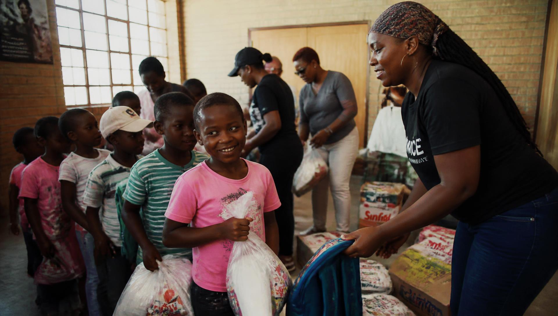 Volunteers distributing food parcels to families at a community hall
